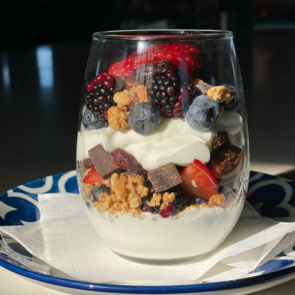 A glass of PIK-NIK Deli + Wine Bar's yogurt parfait with berries, granola, and chocolate chunks.