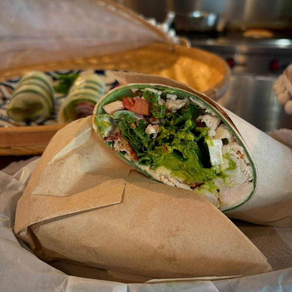 A PIK-NIK Deli + Wine Bar wrap, filled with chicken, lettuce, tomato, and avocado.